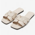Cream interlocking strap faux leather flat slides, pair view