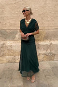 Woman in bottle green V-neck chiffon maxi dress with gold jewellery