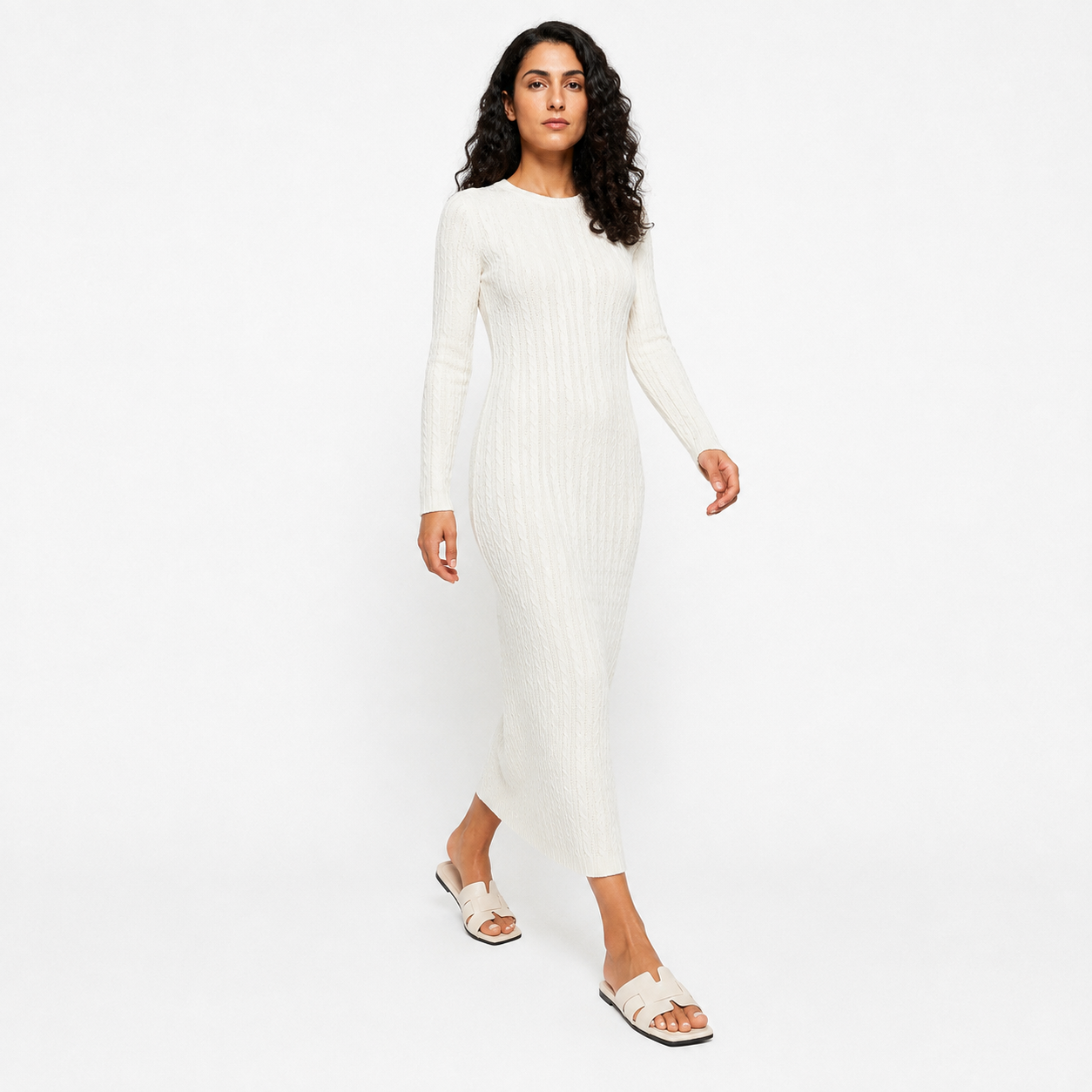 Woman wearing white flat slides with a cream knitted dress, full length