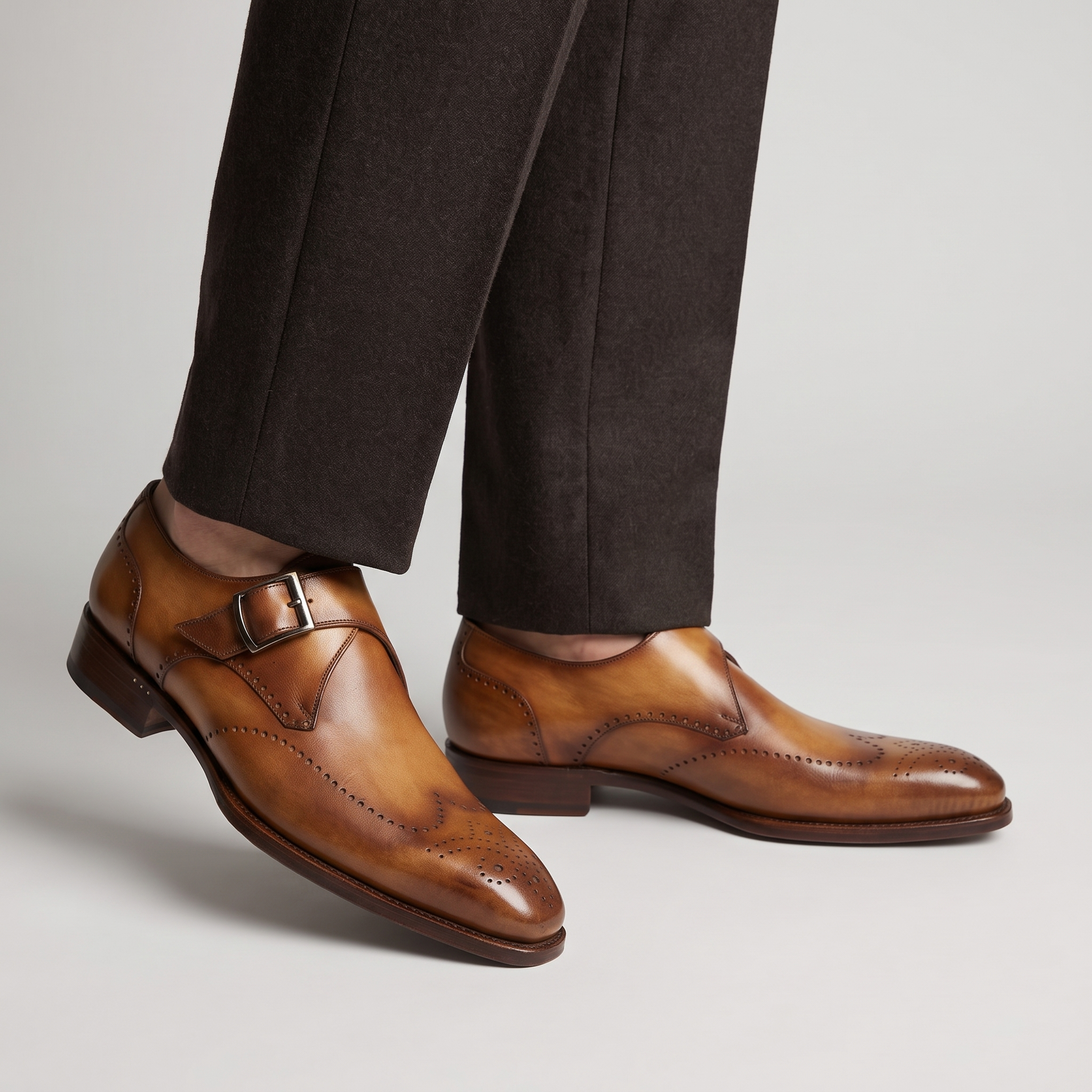 Men's tan wingtip monk strap brogues with silver buckle worn with brown wool trousers