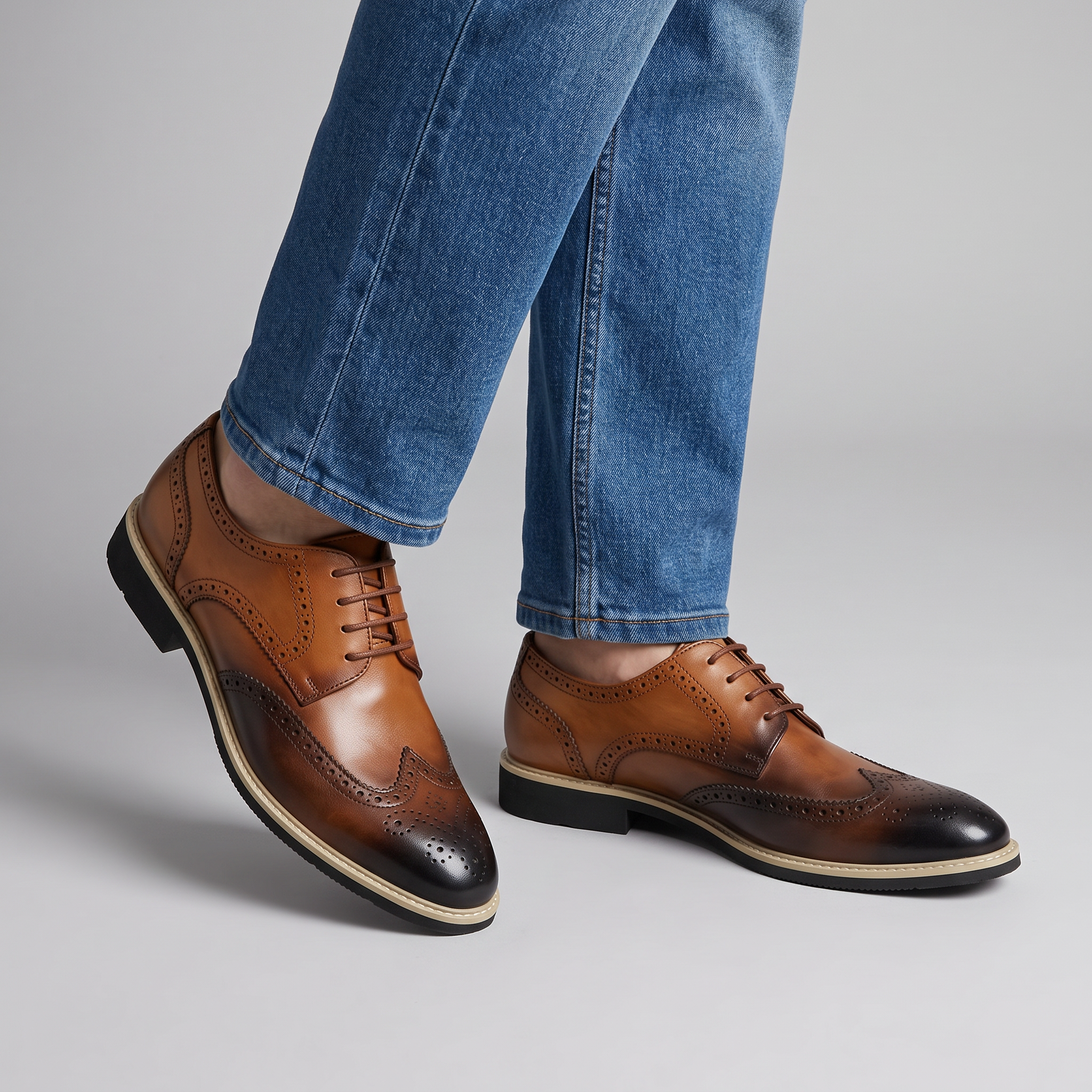 Men's two tone brown wingtip brogues with contrast midsole worn with blue jeans