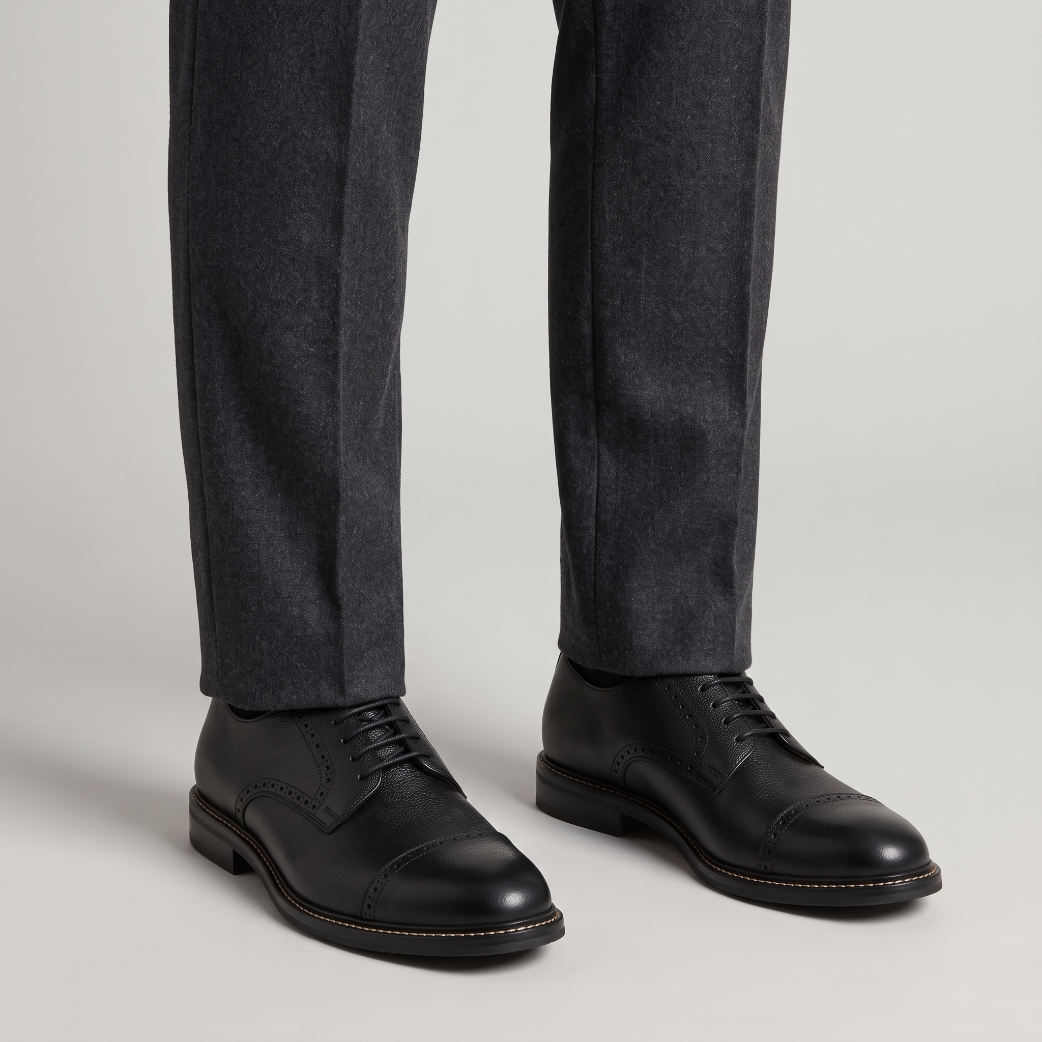 Men's black cap toe Derby shoes with brogue trim worn with charcoal wool trousers