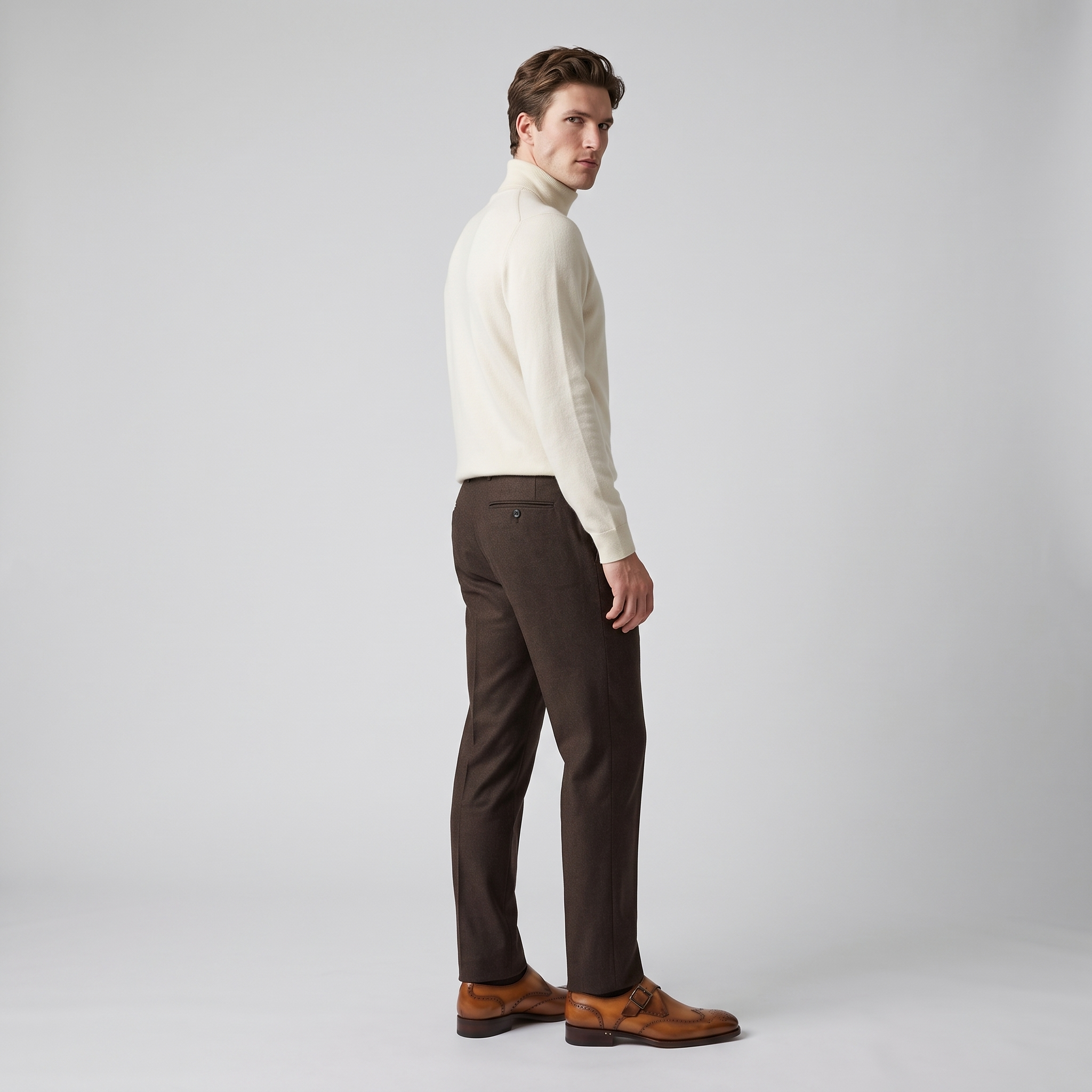 Man wearing tan wingtip monk straps with brown trousers and a cream roll neck