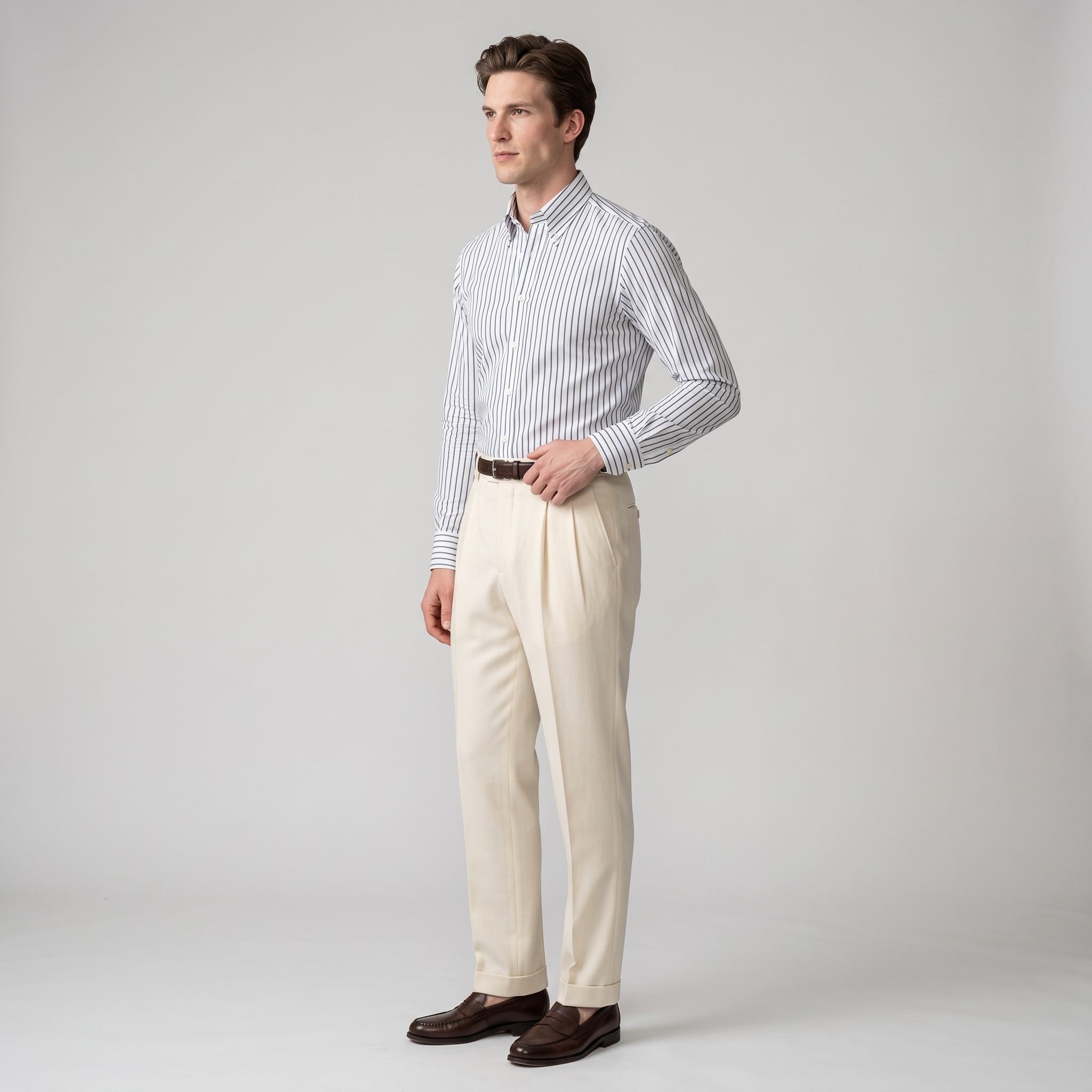 Side view of a navy bengal stripe button-down shirt tucked into cream trousers