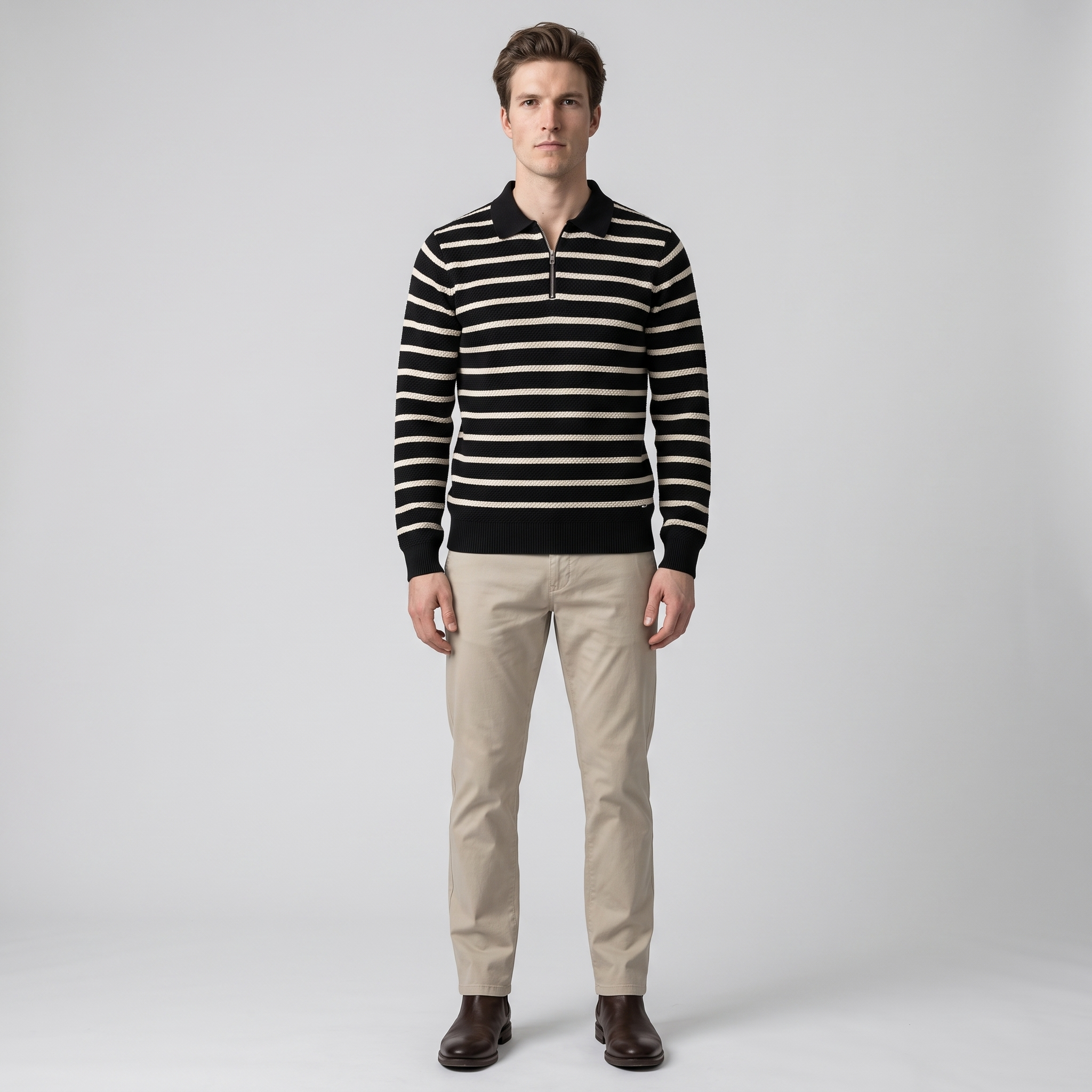 Man wearing a black and cream striped quarter zip knit polo with stone chinos