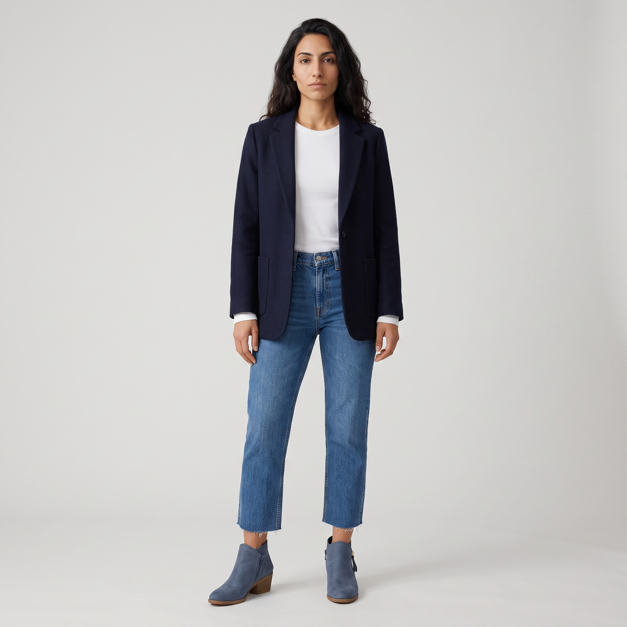 Woman wearing denim blue ankle boots with cropped jeans and a navy blazer
