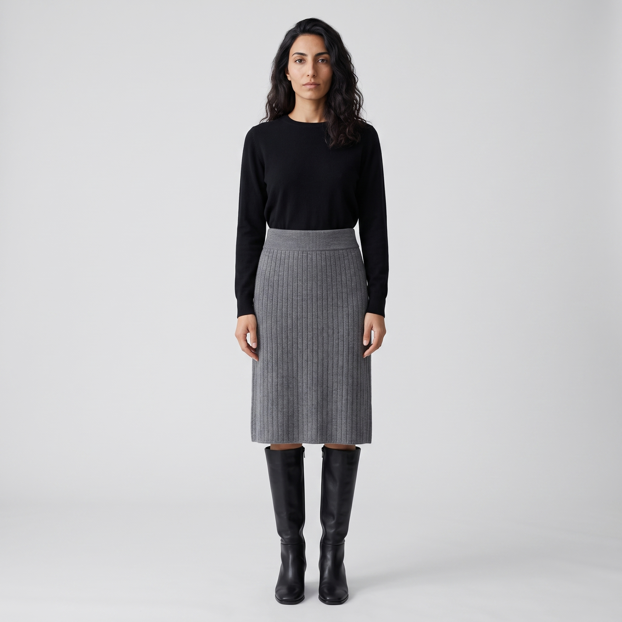 Woman wearing a grey ribbed knit skirt with a black knit top and knee high boots