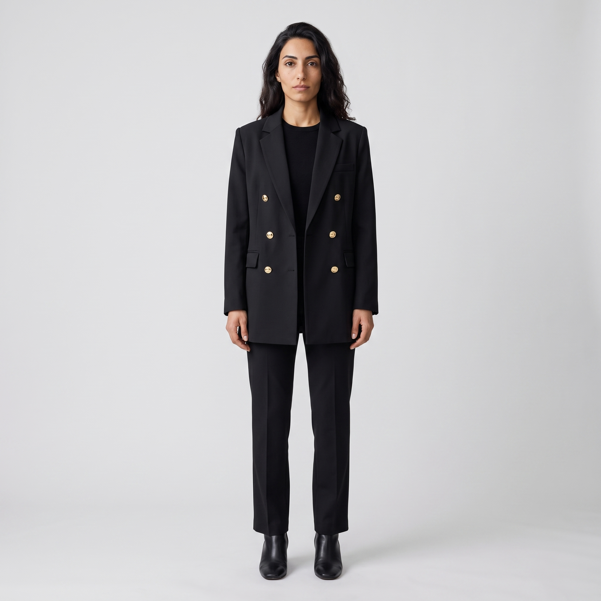 Woman wearing a black longline double breasted blazer with engraved gold buttons