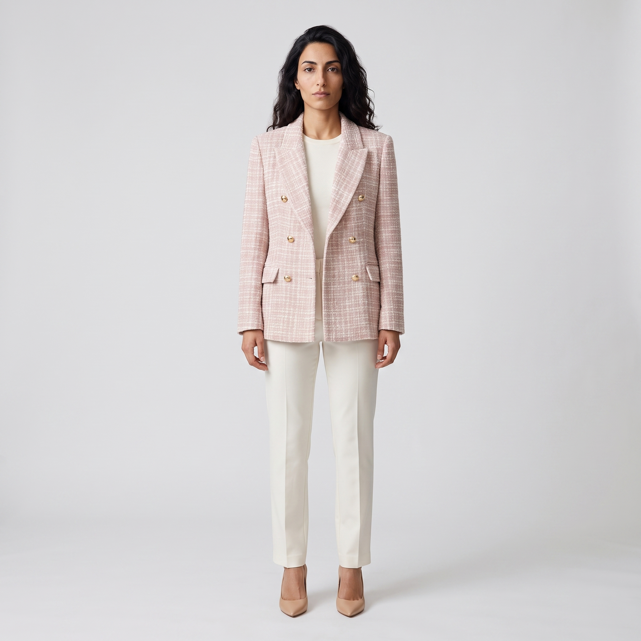 Woman wearing a pink tweed double breasted blazer with a peak lapel and gold buttons