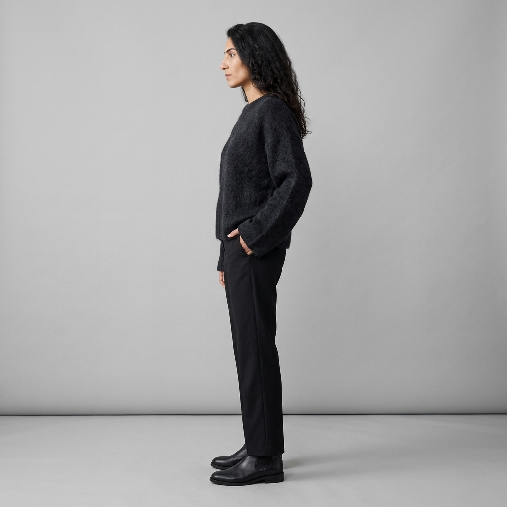 Woman wearing a black brushed fuzzy knit jumper, side view