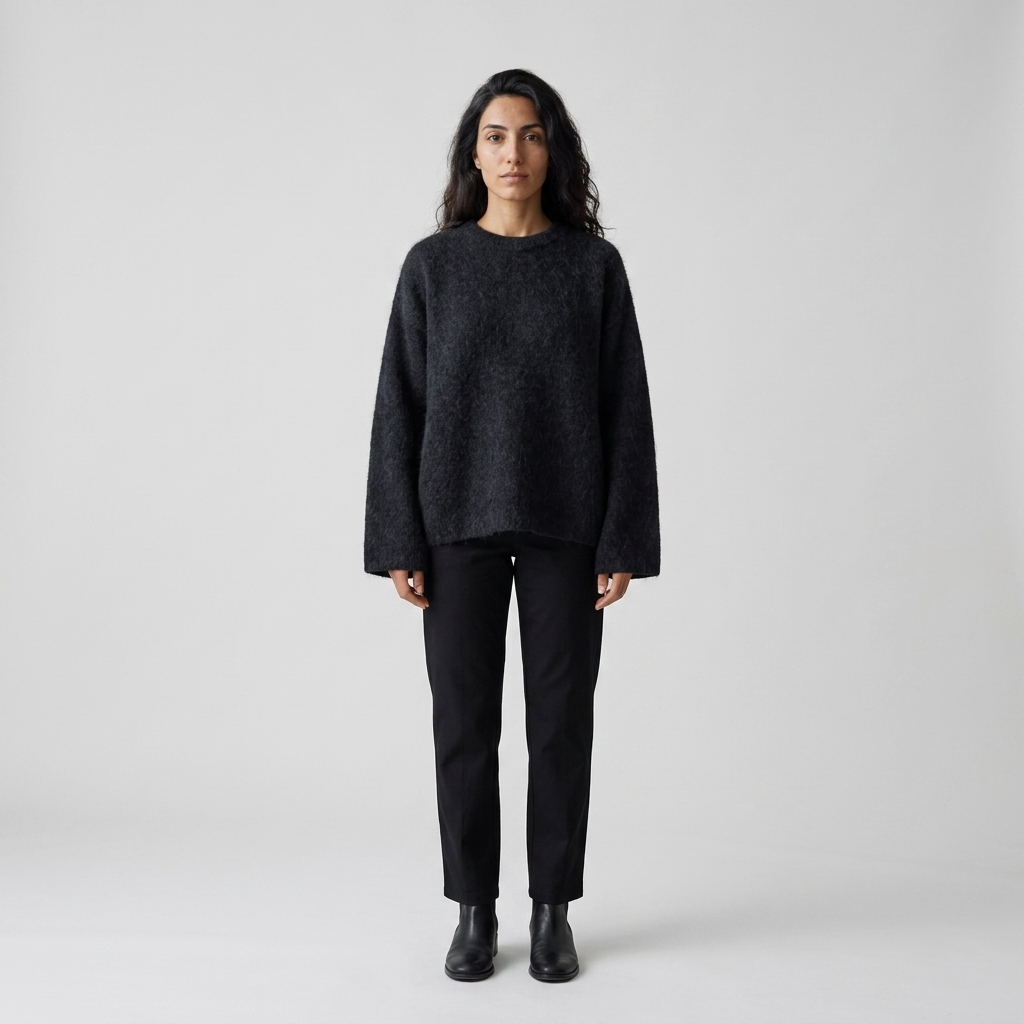 Woman wearing a black brushed fuzzy knit jumper with black trousers, front view