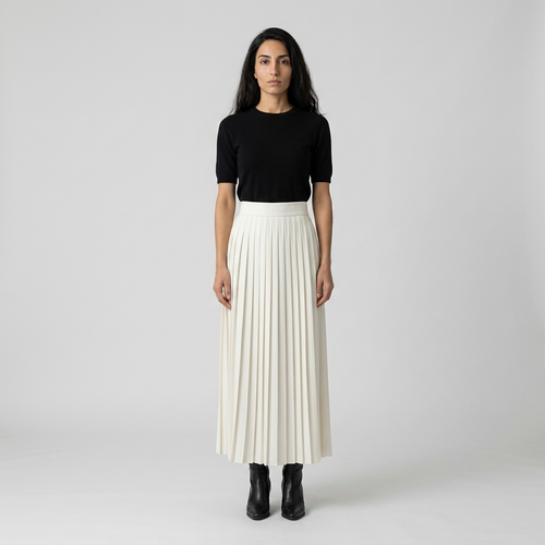 Model wearing ivory pleated maxi skirt with black knit top, front view