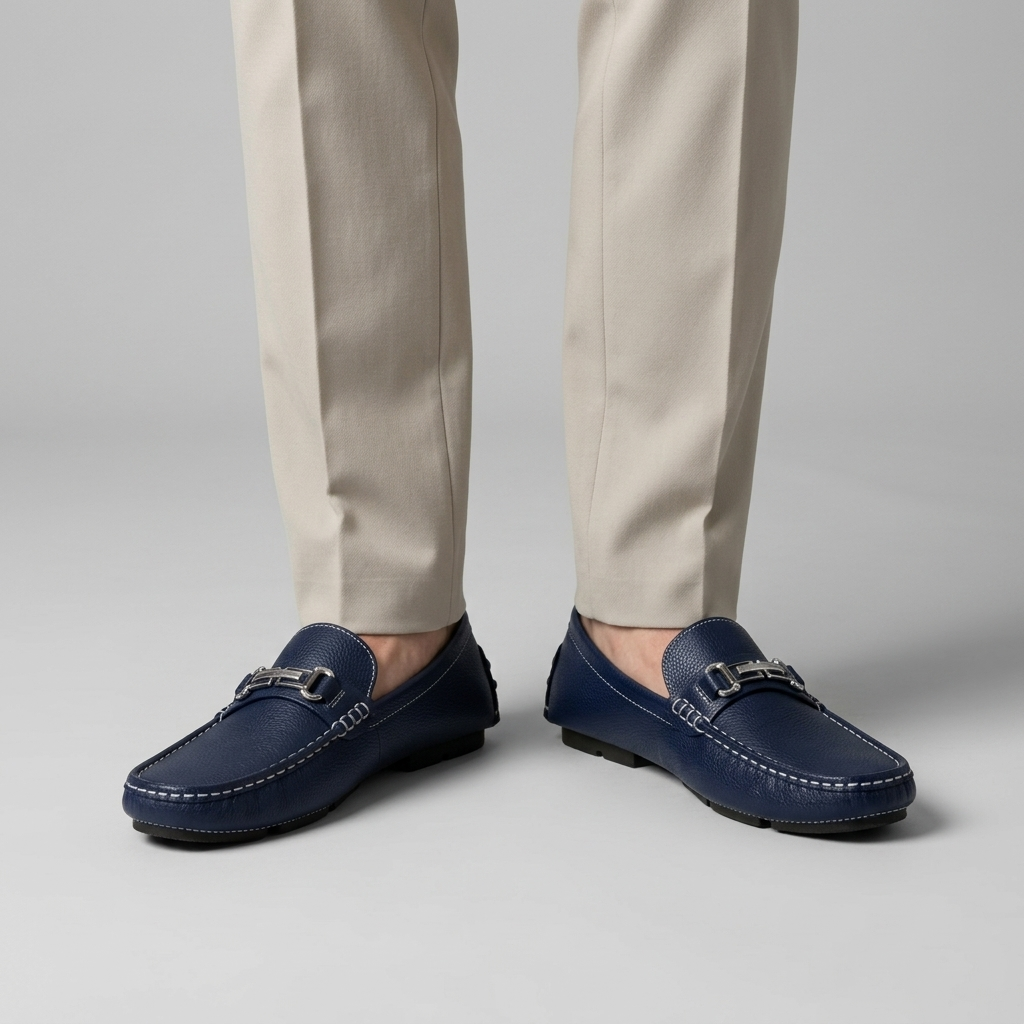 Navy leather driving loafers with a silver bit worn with stone trousers, close view
