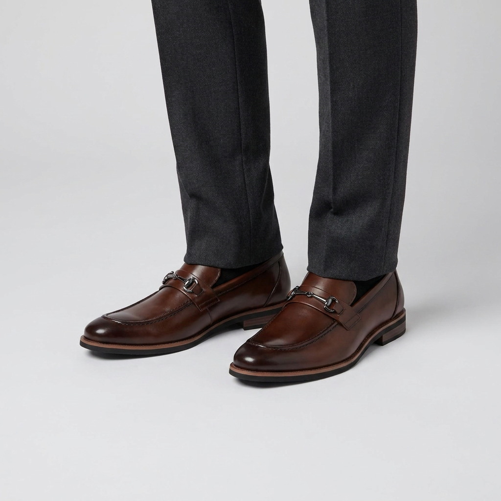 Dark brown polished leather bit loafers worn with charcoal suit trousers, close view