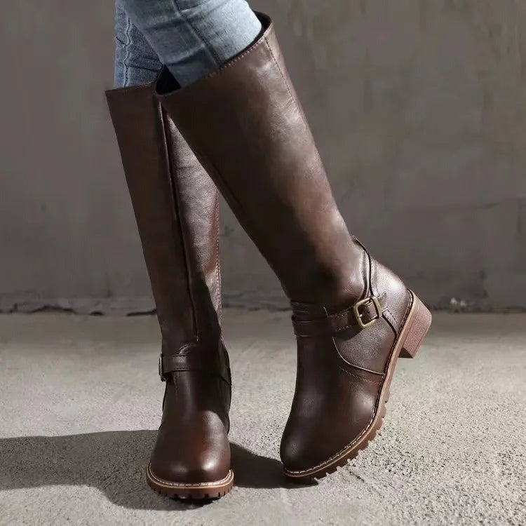 Close view of the flat block heel and textured sole on knee high riding boots