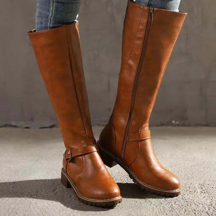 Light brown knee high riding boots worn with slim fitting jeans
