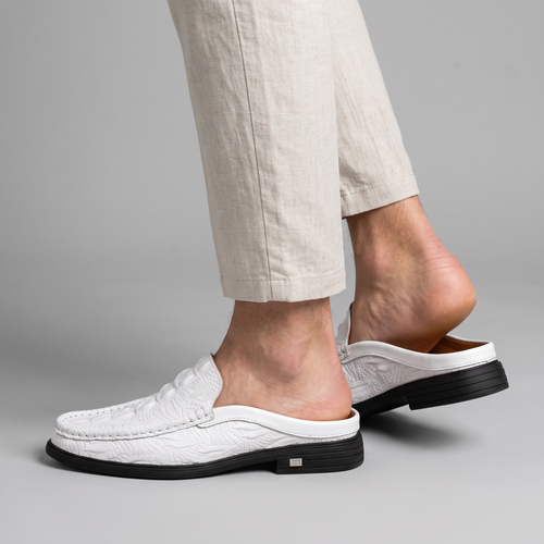 Model wearing the white textured backless mule loafers, studio shot