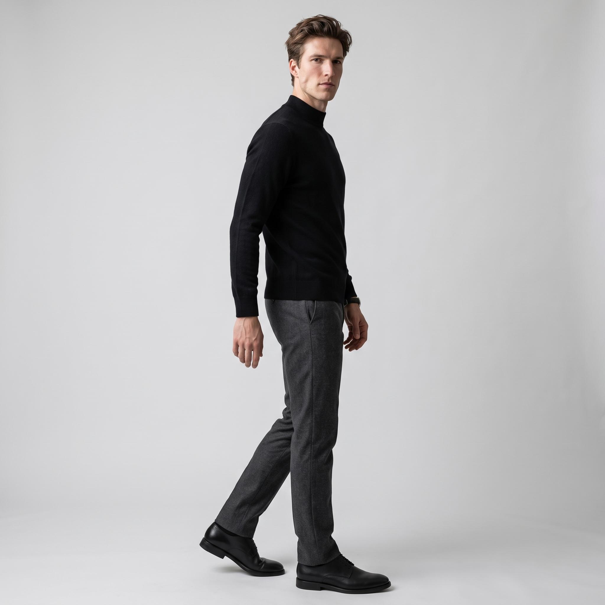Side view of the black mock neck knit jumper worn with charcoal trousers