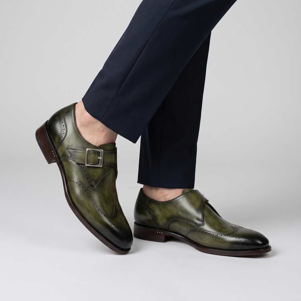 Model wearing the olive green wingtip monk strap shoes with silver buckle, studio shot