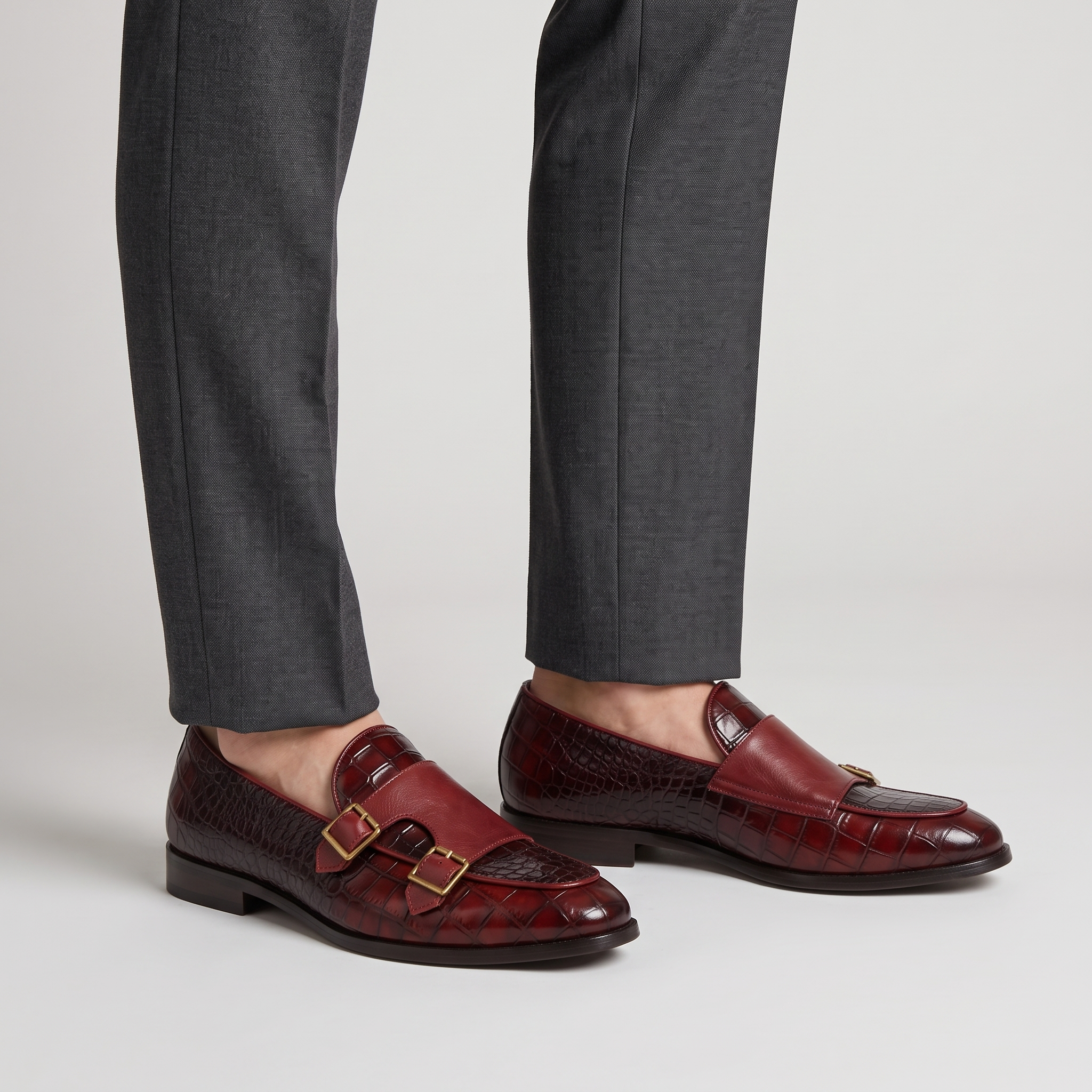 Model wearing the wine red croc effect loafers with double gold buckles, studio shot