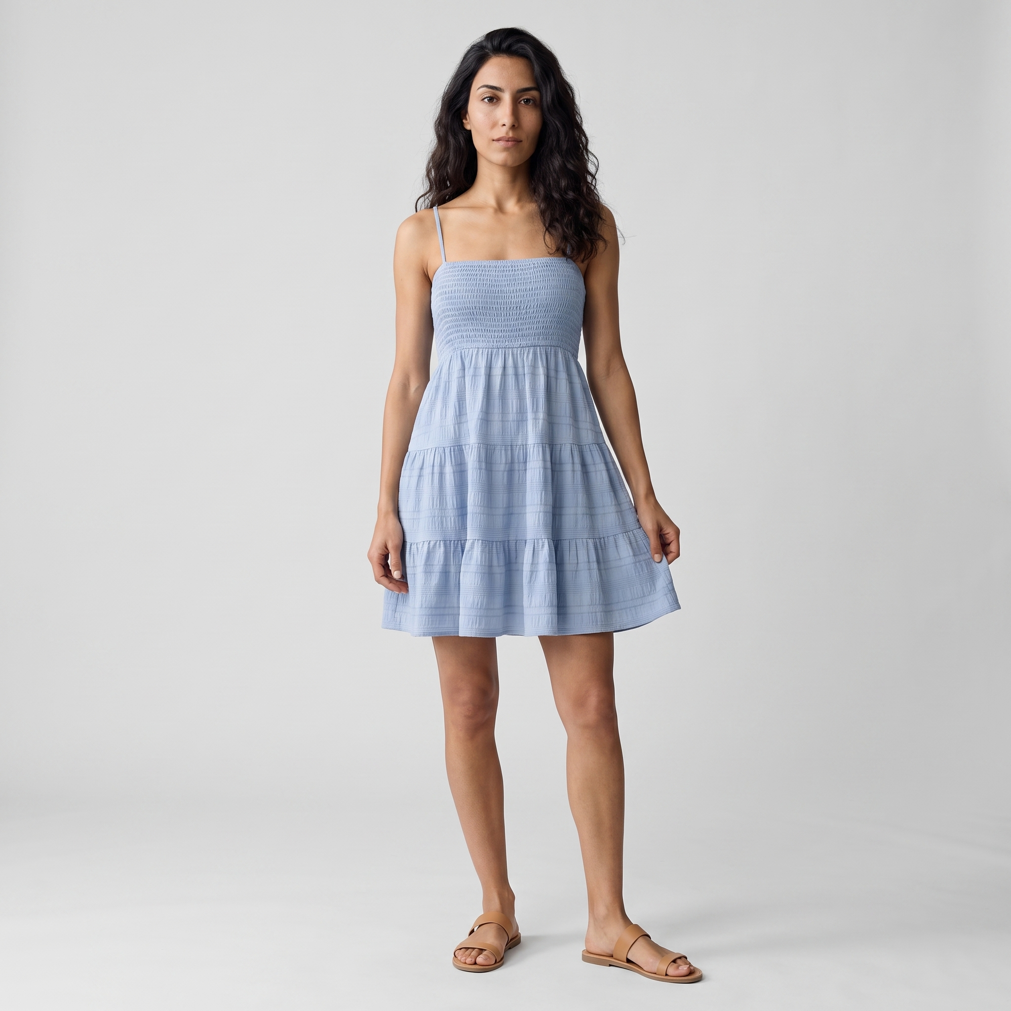 Model wearing the light blue smocked tiered mini sundress, studio shot