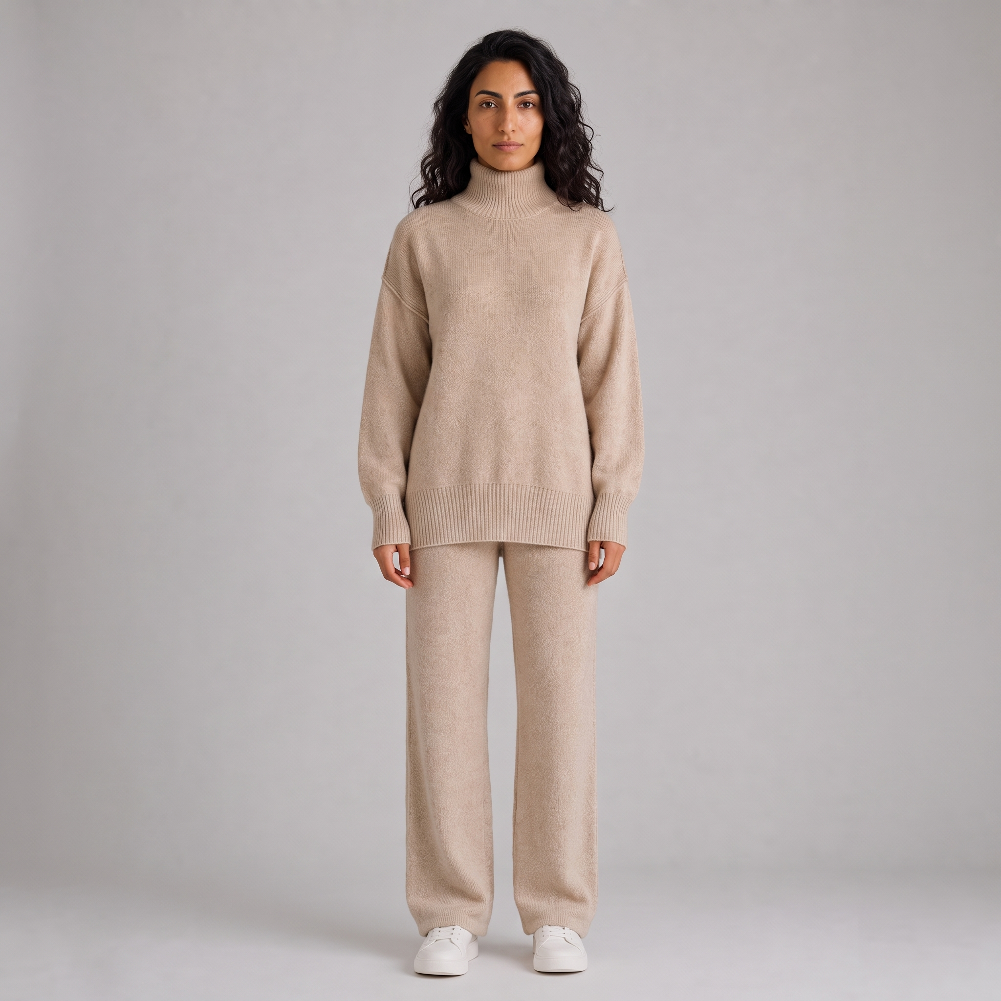 Model wearing the oatmeal knitted roll neck jumper and wide leg trousers set, studio shot