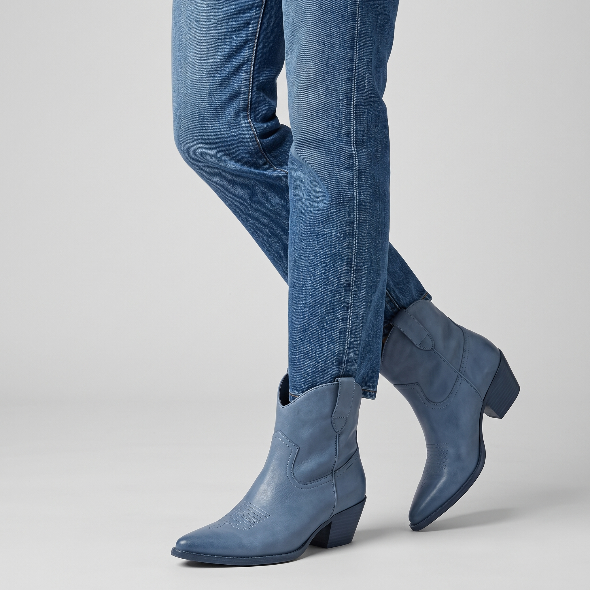 Model wearing the blue western ankle boots with straight leg denim, studio shot