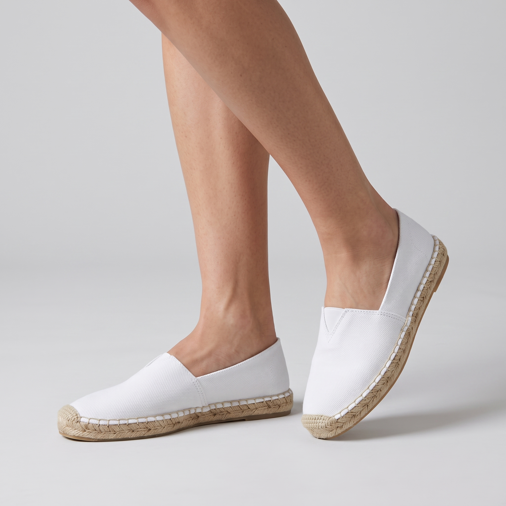 White canvas espadrilles with natural jute sole, worn by a model